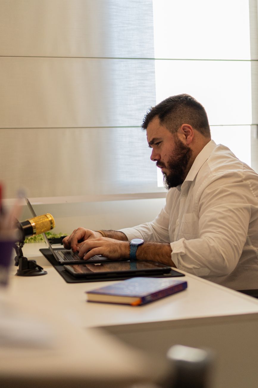 man in shirt sitting and working on laptop